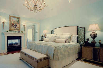 Diseño de dormitorio principal clásico grande con suelo de madera clara, chimenea de doble cara, marco de chimenea de metal y con escritorio