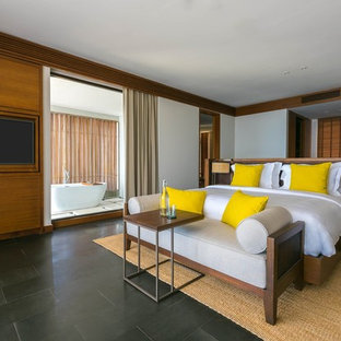 Imagen de dormitorio principal, tropical, sin chimenea, con paredes blancas y suelo negro