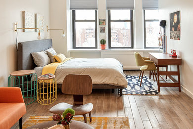 Kleines Mid-Century Schlafzimmer mit weißer Wandfarbe, hellem Holzboden und braunem Boden in New York