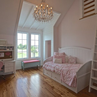 Modelo de dormitorio tipo loft, costero, sin chimenea, con paredes rosas y suelo de madera en tonos medios
