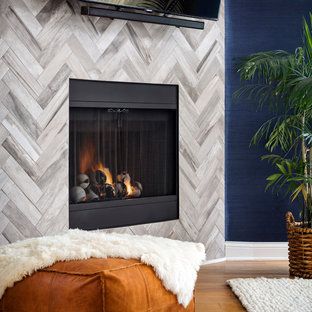 Foto de dormitorio principal, costero, de tamaño medio, con paredes azules, suelo de madera clara, chimenea de esquina, marco de chimenea de baldosas y/o azulejos y suelo marrón