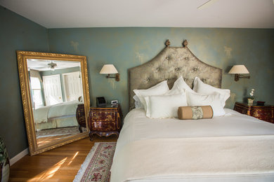 Modelo de habitación de invitados tradicional grande sin chimenea con paredes azules y suelo de madera en tonos medios