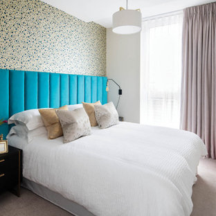 This is an example of a contemporary bedroom in London with multi-coloured walls, carpet, no fireplace, beige floors and wallpapered walls.