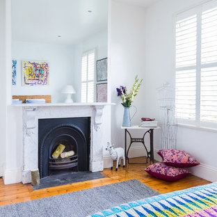 Photo of an eclectic guest bedroom in Melbourne with a standard fireplace, white walls, medium hardwood floors and a stone fireplace surround.