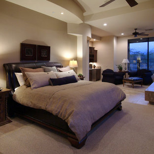 Großes Mediterranes Hauptschlafzimmer mit Kaminumrandung aus Stein, Eckkamin, beiger Wandfarbe, Travertin und braunem Boden in Phoenix