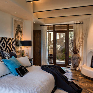 Ejemplo de dormitorio principal, de estilo americano, de tamaño medio, con paredes beige, marco de chimenea de yeso, suelo de madera oscura, chimenea de esquina y suelo marrón