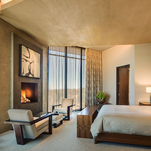 Imagen de dormitorio principal, contemporáneo, de tamaño medio, con paredes beige, moqueta, chimenea tradicional, suelo beige y marco de chimenea de hormigón