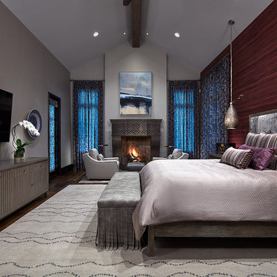 Large transitional master medium tone wood floor and brown floor bedroom photo in Dallas with a standard fireplace, a stone fireplace and gray walls