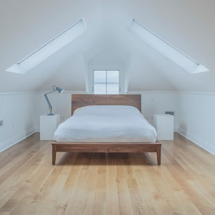 Modelo de dormitorio tipo loft, nórdico, de tamaño medio, sin chimenea, con paredes blancas, suelo de madera en tonos medios y suelo marrón