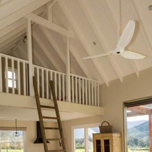 Foto de dormitorio tipo loft, de estilo de casa de campo, pequeño, con paredes beige, suelo de cemento, chimenea tradicional y marco de chimenea de piedra