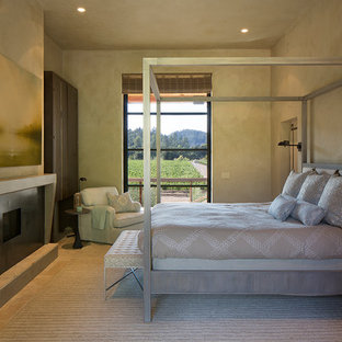 Imagen de dormitorio principal, de estilo de casa de campo, de tamaño medio, con paredes beige, suelo de piedra caliza, chimenea tradicional y marco de chimenea de metal