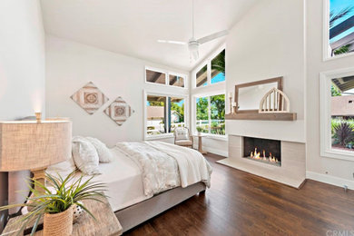 Example of a mid-sized transitional guest laminate floor and brown floor bedroom design in Orange County with gray walls, a standard fireplace and a tile fireplace