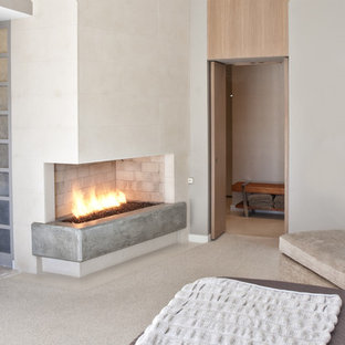 Modernes Schlafzimmer mit Kaminumrandung aus Beton und Eckkamin in Dallas