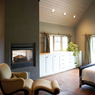 Imagen de dormitorio ecléctico con marco de chimenea de hormigón y chimenea de doble cara