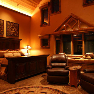 Diseño de dormitorio principal, rústico, extra grande, con paredes beige, chimenea de doble cara y marco de chimenea de piedra