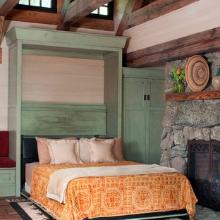 Ejemplo de habitación de invitados rural, pequeña, con suelo de madera en tonos medios, chimenea tradicional y marco de chimenea de piedra