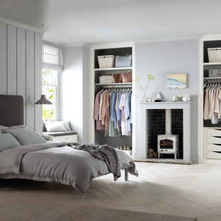 Imagen de habitación de invitados costera con suelo de madera clara, estufa de leña y suelo blanco