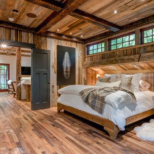 Diseño de dormitorio principal, rústico, grande, sin chimenea, con paredes marrones y suelo de madera en tonos medios