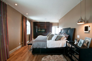 Large minimalist master light wood floor bedroom photo in Calgary with beige walls, a standard fireplace and a wood fireplace surround