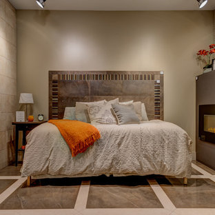 Diseño de dormitorio principal, contemporáneo, de tamaño medio, con paredes beige, marco de chimenea de piedra, suelo de mármol, chimenea lineal y suelo marrón