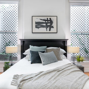 Inspiration for a scandinavian bedroom in Sydney with white walls, medium hardwood floors and brown floor.