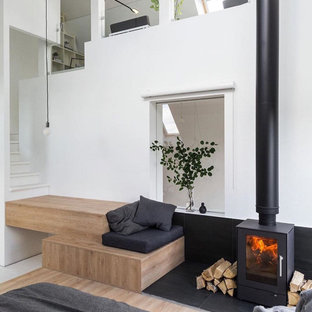Diseño de dormitorio nórdico, pequeño, con paredes blancas, suelo de madera clara y estufa de leña