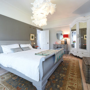 Traditional master bedroom in Manchester with grey walls, light hardwood flooring and beige floors.