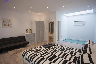 Large modern master bedroom in London with white walls and light hardwood flooring.