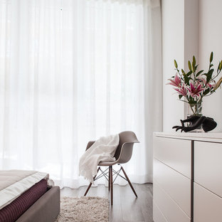 Example of a mid-sized minimalist guest ceramic tile bedroom design in Miami with white walls and no fireplace
