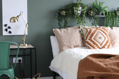 Ejemplo de habitación de invitados minimalista de tamaño medio sin chimenea con paredes verdes, suelo laminado y suelo marrón