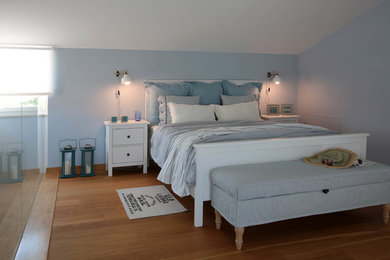Foto de habitación de invitados costera de tamaño medio con paredes azules, suelo de madera en tonos medios y suelo beige