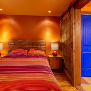 Diseño de dormitorio principal, de estilo americano, de tamaño medio, con parades naranjas y suelo de madera en tonos medios