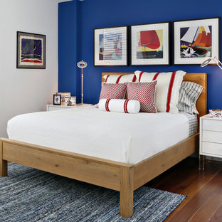 Imagen de dormitorio marinero, de tamaño medio, sin chimenea, con suelo de madera en tonos medios, paredes azules y suelo naranja