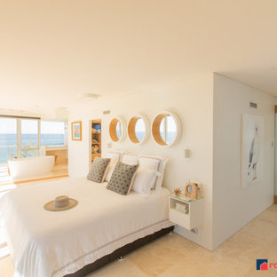 Diseño de dormitorio principal, costero, de tamaño medio, con paredes blancas y suelo de travertino