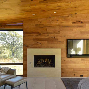 Foto de dormitorio principal, contemporáneo, de tamaño medio, con suelo de piedra caliza, chimenea tradicional, marco de chimenea de piedra y suelo beige