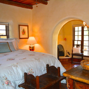 Foto de habitación de invitados mediterránea, grande, con paredes beige, suelo de baldosas de terracota, chimenea de esquina y marco de chimenea de yeso