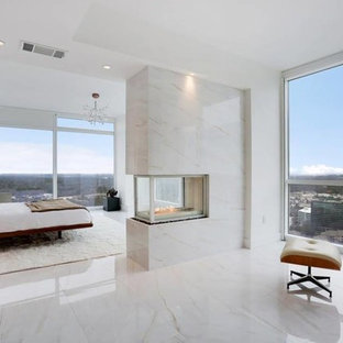 Diseño de dormitorio principal, minimalista, grande, con paredes blancas, suelo de mármol, chimenea de doble cara, marco de chimenea de piedra y suelo blanco