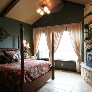Diseño de dormitorio principal, clásico, grande, con paredes verdes, suelo de travertino, chimenea de esquina, marco de chimenea de piedra y suelo marrón