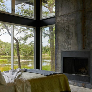 Modelo de dormitorio clásico renovado, de tamaño medio, con suelo de cemento, chimenea tradicional y marco de chimenea de metal