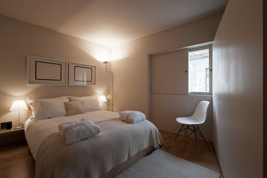 他の地域にある小さなモダンスタイルのおしゃれな客用寝室 (白い壁、無垢フローリング) のインテリア