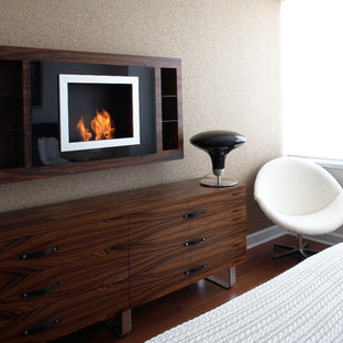 Ejemplo de dormitorio principal, actual, de tamaño medio, con paredes blancas, suelo de madera oscura, chimeneas suspendidas, marco de chimenea de metal y suelo marrón