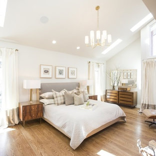 Foto de dormitorio principal, tradicional renovado, grande, con paredes blancas, suelo de madera en tonos medios, chimenea tradicional y marco de chimenea de ladrillo