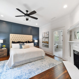 Mittelgroßes Klassisches Hauptschlafzimmer mit bunten Wänden, dunklem Holzboden, Eckkamin, Kaminumrandung aus Holz und braunem Boden in Atlanta