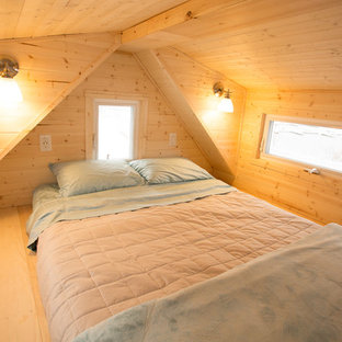Esempio di una piccola camera da letto stile loft american style con pareti marroni, pavimento in legno verniciato e camino sospeso
