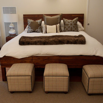 The master bed goes glam with stunning pillows and wool plaid ottomans and bench