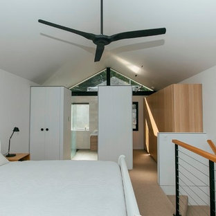 Diseño de dormitorio tipo loft, contemporáneo, pequeño, sin chimenea, con paredes blancas, moqueta y marco de chimenea de ladrillo