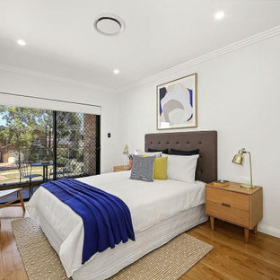 This is an example of a mid-sized contemporary guest bedroom in Sydney with grey walls, medium hardwood floors and brown floor.