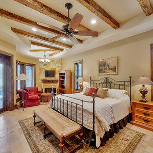 Ejemplo de dormitorio principal, tradicional, grande, con paredes beige, suelo de travertino, chimenea tradicional, marco de chimenea de baldosas y/o azulejos y suelo marrón