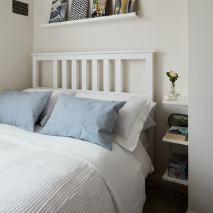 Modelo de dormitorio actual, pequeño, con paredes blancas, moqueta, chimenea de esquina, marco de chimenea de metal y suelo beige