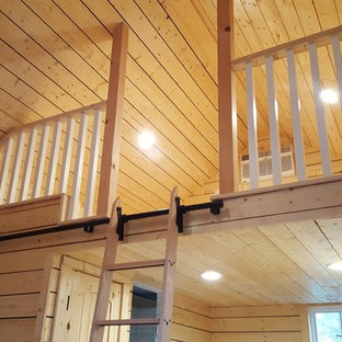 Ejemplo de dormitorio tipo loft, de estilo americano, pequeño, con paredes amarillas y suelo de madera clara